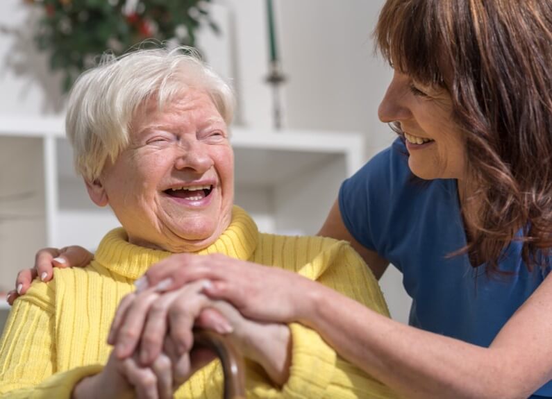  Préposée aux bénéficiaires à domicile riant avec une personne agée 